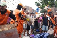 Pemerintah Kota (Pemkot) Administrasi Jakarta Barat mengerahkan puluhan truk dan ratusan personel gabungan bersama warga untuk membersihkan sampah pascabanjir secara serentak di delapan kecamatan, Minggu (25/1/2026).