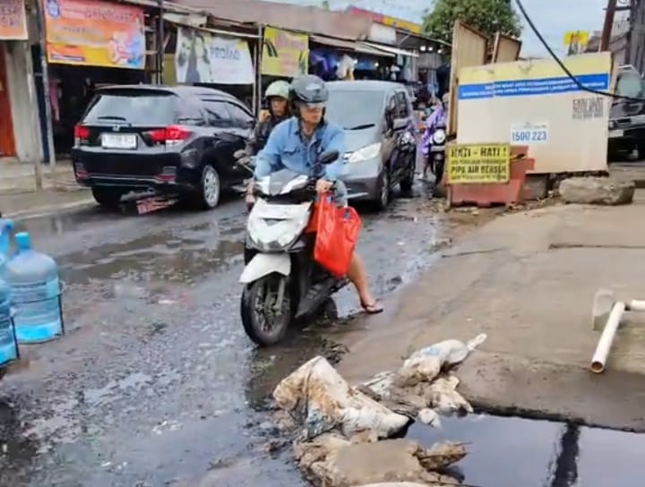 Warga mengeluhkan bau menyengat dari saluran air yang meluber ke badan Jalan Satu Maret, Kelurahan Pegadungan, Kecamatan Kalideres, Jakarta Barat