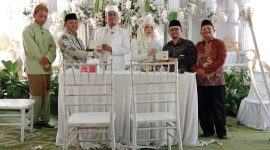 Pasangan pengantin menerima dokumen pernikahan dalam Program Nikah Gratis yang diinisiasi Kepala Kampung Bandar Sari, Tarwani. Program tersebut mencakup pengurusan administrasi nikah hingga penerbitan buku nikah secara gratis bagi warga Kampung Bandar Sari.
