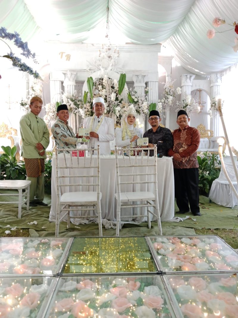 Pasangan pengantin menerima dokumen pernikahan dalam Program Nikah Gratis yang diinisiasi Kepala Kampung Bandar Sari, Tarwani. Program tersebut mencakup pengurusan administrasi nikah hingga penerbitan buku nikah secara gratis bagi warga Kampung Bandar Sari.