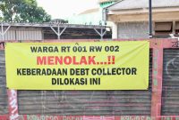 Spanduk penolakan terhadap aktivitas debt collector terpasang di kawasan RT 001/RW 002 sebagai bentuk aspirasi warga yang menginginkan lingkungan tetap aman, tertib, dan bebas dari potensi keributan di ruang publik. Warga berharap setiap proses penagihan pembiayaan dilakukan sesuai ketentuan hukum tanpa mengganggu ketertiban masyarakat.
Foto: Dok. Tikampost.id.