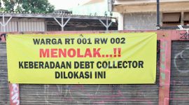 Spanduk penolakan terhadap aktivitas debt collector terpasang di kawasan RT 001/RW 002 sebagai bentuk aspirasi warga yang menginginkan lingkungan tetap aman, tertib, dan bebas dari potensi keributan di ruang publik. Warga berharap setiap proses penagihan pembiayaan dilakukan sesuai ketentuan hukum tanpa mengganggu ketertiban masyarakat.
Foto: Dok. Tikampost.id.