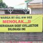 Spanduk penolakan terhadap aktivitas debt collector terpasang di kawasan RT 001/RW 002 sebagai bentuk aspirasi warga yang menginginkan lingkungan tetap aman, tertib, dan bebas dari potensi keributan di ruang publik. Warga berharap setiap proses penagihan pembiayaan dilakukan sesuai ketentuan hukum tanpa mengganggu ketertiban masyarakat.
Foto: Dok. Tikampost.id.