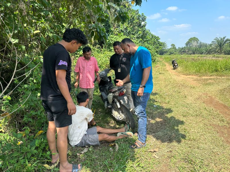 Petugas bersama sejumlah warga terlihat berada di lokasi saat melakukan pemeriksaan terhadap seorang pria dan sepeda motor di kawasan jalan perkebunan. Pemeriksaan tersebut diduga berkaitan dengan pengungkapan kasus yang tengah ditangani aparat. (Dok: Tikampost.id)
