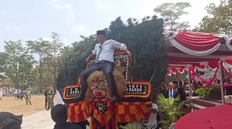 Kadis Kominfo Way Kanan, Yusron Lutfi, S.H., M.M., turut menaiki Dadak Merak dalam pertunjukan Reog Ponorogo pada rangkaian peringatan HUT ke-81 Kemerdekaan Republik Indonesia di Kabupaten Way Kanan, Senin (17/8/2026). Aksi tersebut mendapat sambutan meriah dan tepuk tangan dari masyarakat serta tamu undangan yang hadir.
