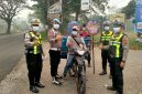 Personel Polres Dharmasraya membagikan masker kepada masyarakat yang melintas di Jalan Lintas Sumatera (Jalinsum), kawasan Gunung Medan, Kecamatan Sitiung, Kamis (8/10/2026), di tengah kondisi kabut asap