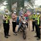 Personel Polres Dharmasraya membagikan masker kepada masyarakat yang melintas di Jalan Lintas Sumatera (Jalinsum), kawasan Gunung Medan, Kecamatan Sitiung, Kamis (8/10/2026), di tengah kondisi kabut asap